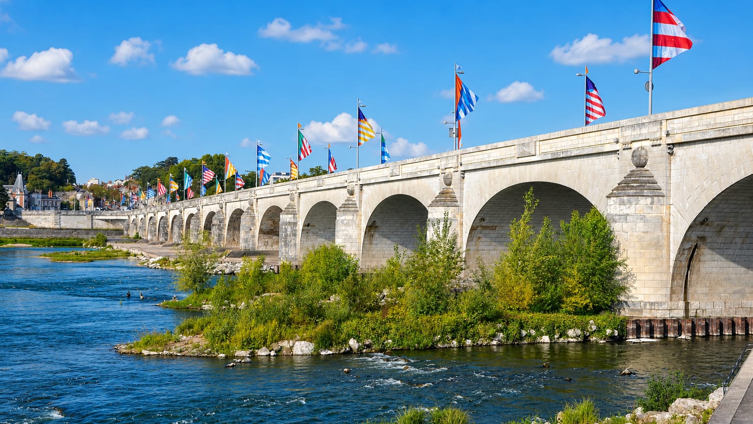 Flag-lined stone arch bridge over the Loire river at Tours, France, on a sunny day