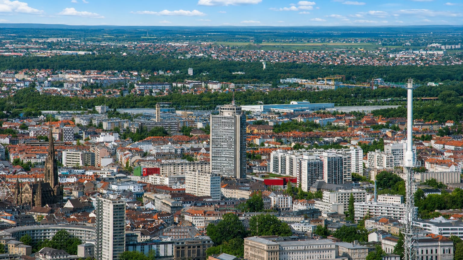 Aerial view of Mulhouse with the dark Gothic spire of Temple Saint-Etienne among tower blocks and rooftops