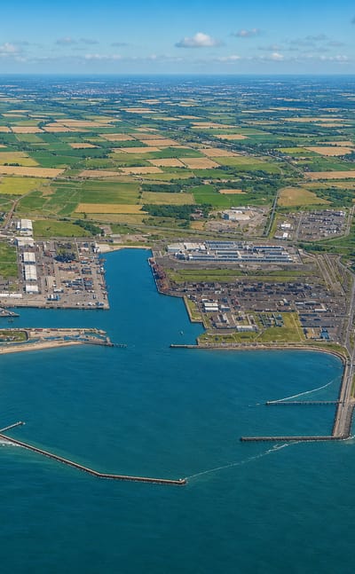 Aerial view of Dunkirk's port, breakwaters and beaches with flat farmland stretching inland.