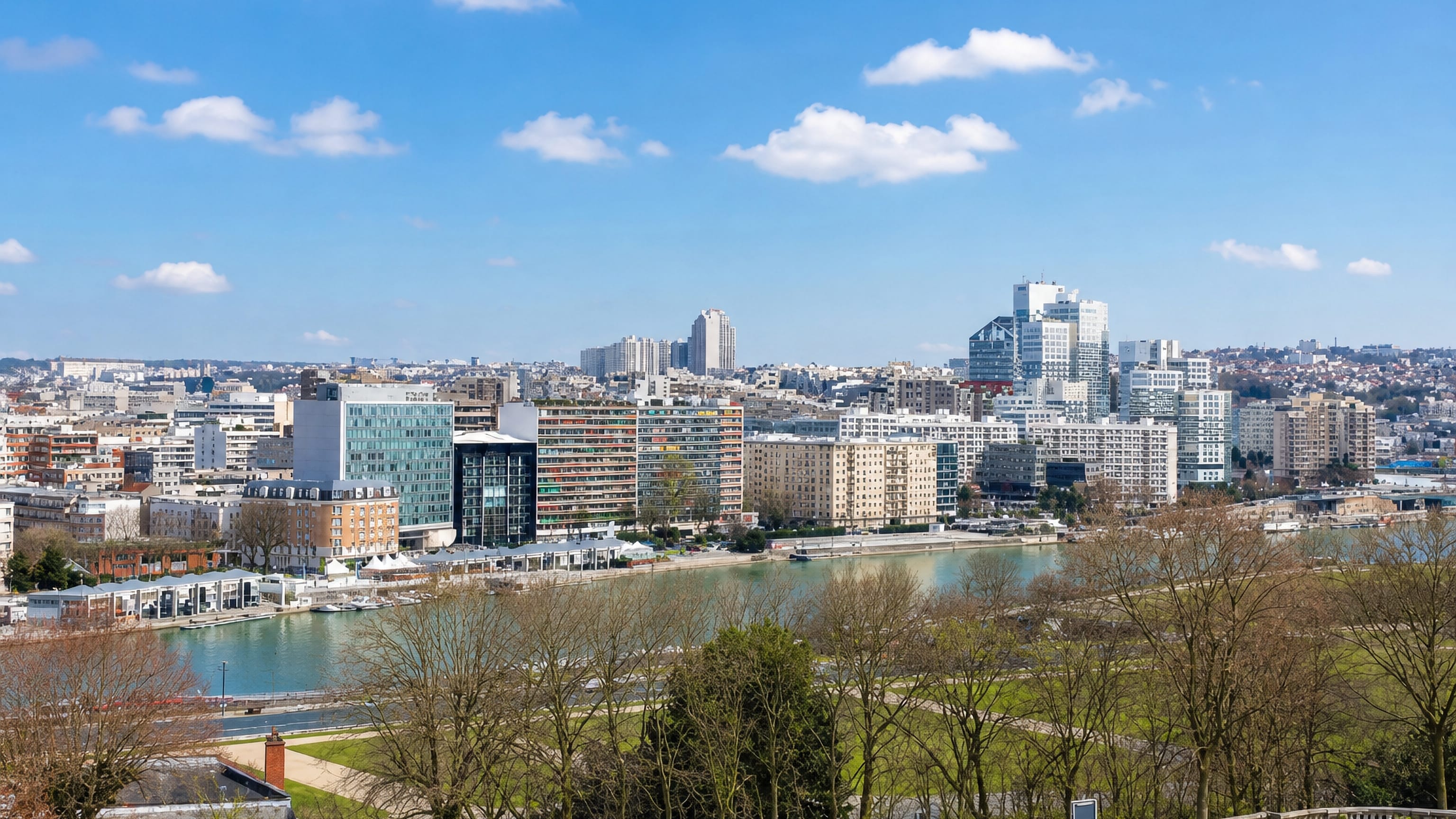Boulogne-Billancourt's Seine-side apartment blocks and office towers seen across the river from a park terrace.