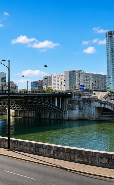 The Seine and a stone arch bridge at Neuilly-sur-Seine with the La Defense skyscraper skyline rising behind
