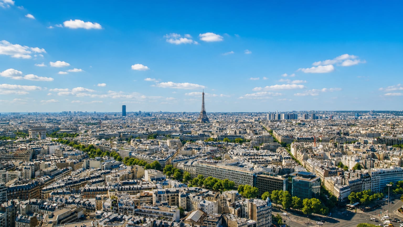Paris skyline with the Eiffel Tower and Montparnasse Tower rising over Haussmannian rooftops under a bright sky.