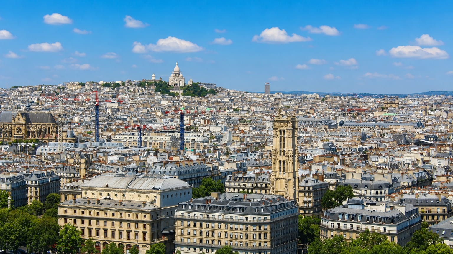 Paris Montmartre skyline with the white Sacre-Coeur basilica crowning the hill above the 18th arrondissement rooftops.