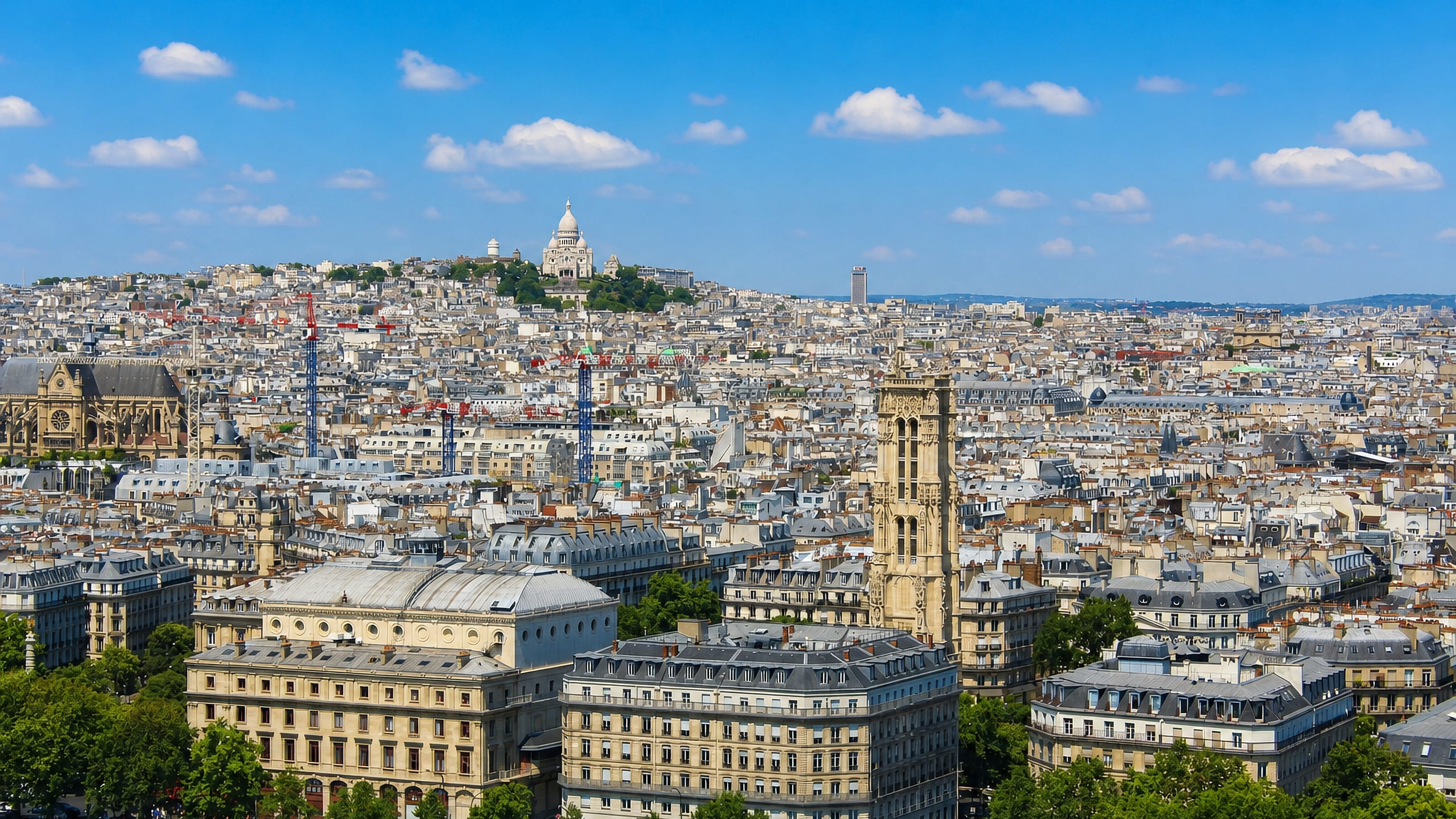 Paris Montmartre skyline with the white Sacre-Coeur basilica crowning the hill above the 18th arrondissement rooftops.
