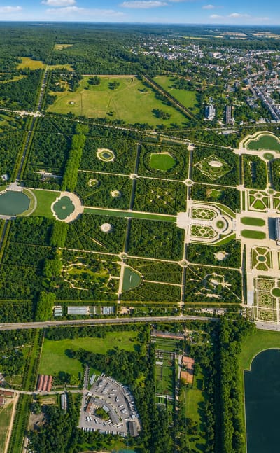 Aerial view of the Palace of Versailles, its formal gardens and Grand Canal beside the town