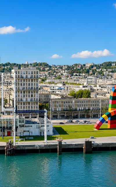 Le Havre waterfront with the Saint-Joseph church tower and the colourful Catene de Conteneurs sculpture by the harbour.
