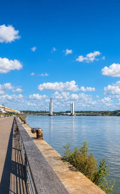 Bordeaux Garonne riverfront quay with waterside terraces and the Chaban-Delmas lift bridge in the distance.