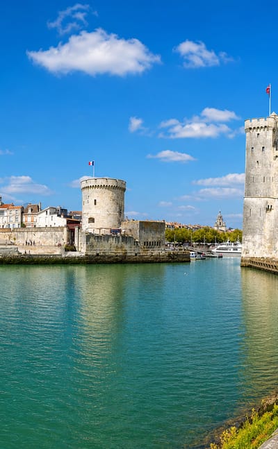 La Rochelle old port entrance framed by its three medieval towers under a bright blue sky.