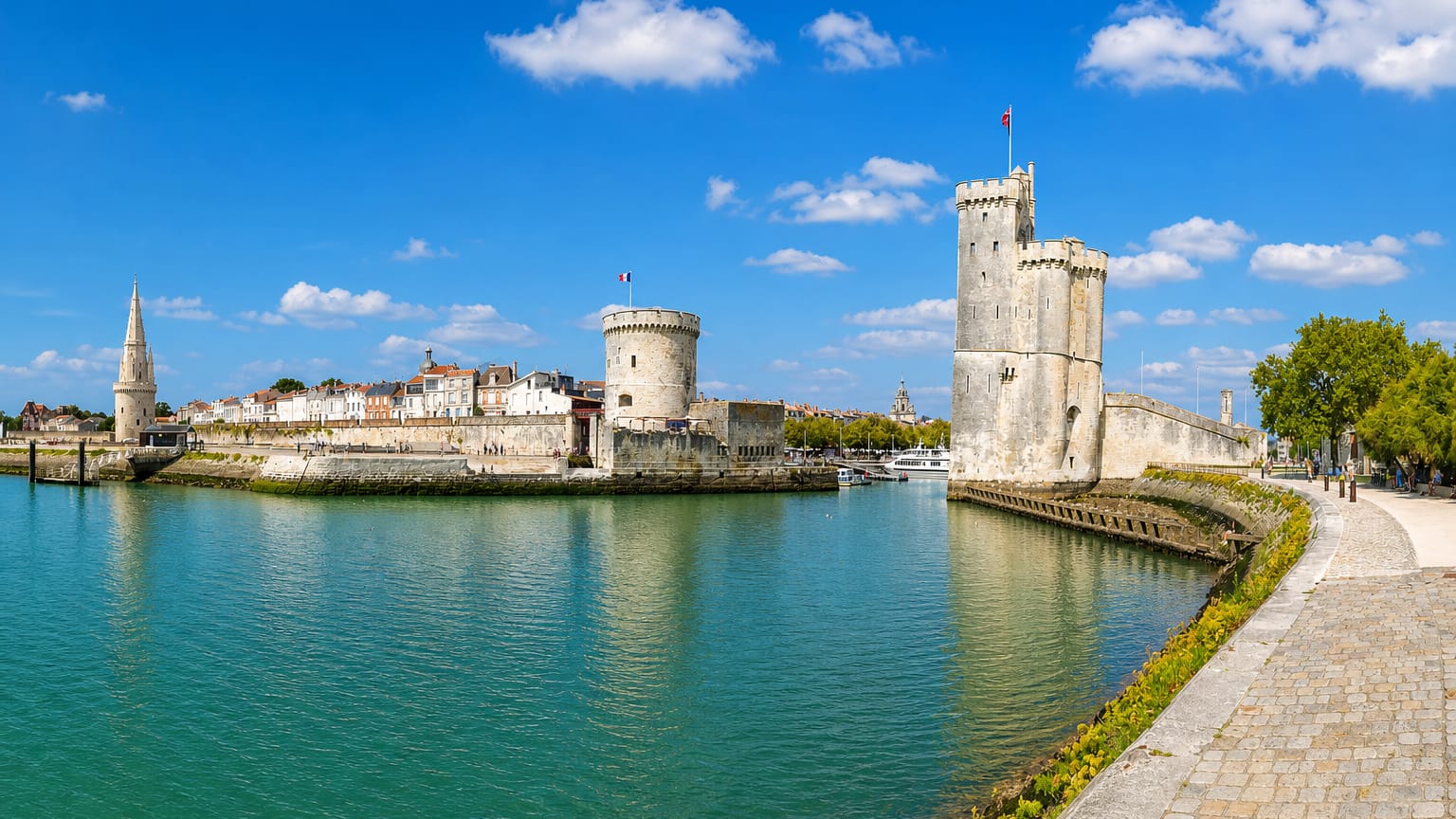 La Rochelle old port entrance framed by its three medieval towers under a bright blue sky.