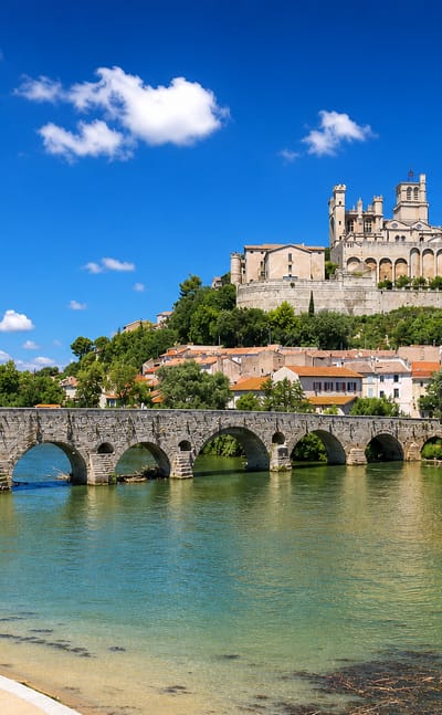 Beziers' Cathedral of Saint-Nazaire on the hill above the Orb river and the old multi-arched stone bridge