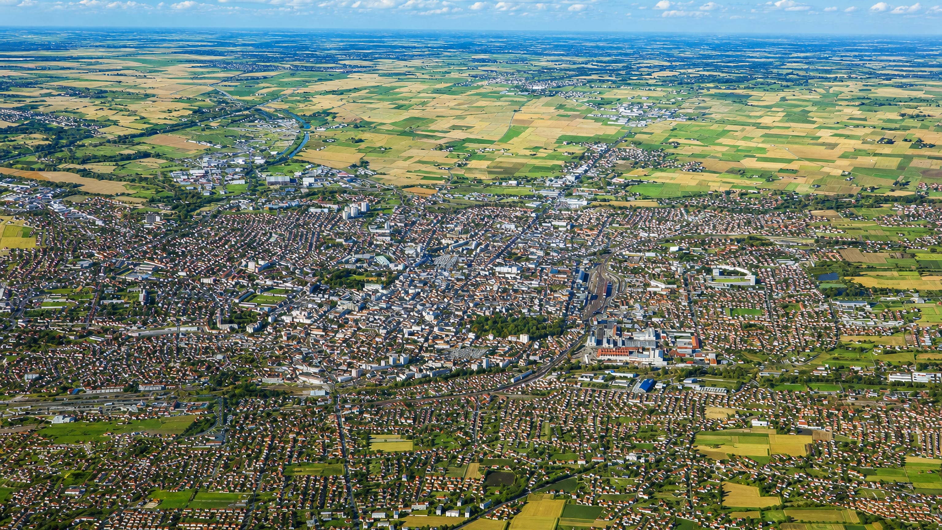 High aerial of Tarbes in Occitanie, its dense town centre spreading out into surrounding farmland
