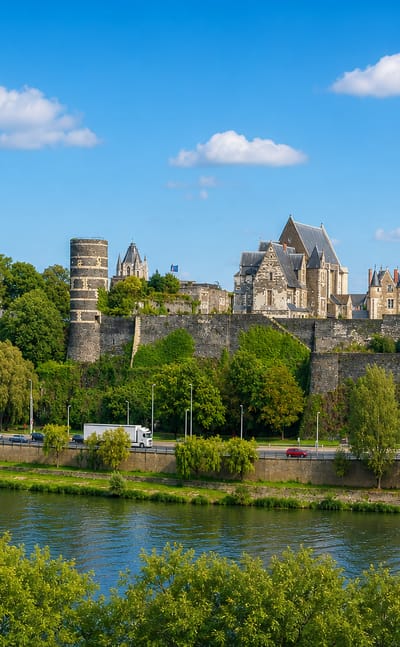 The Chateau d'Angers fortress and twin cathedral spires rising above the Maine river in Angers, France.