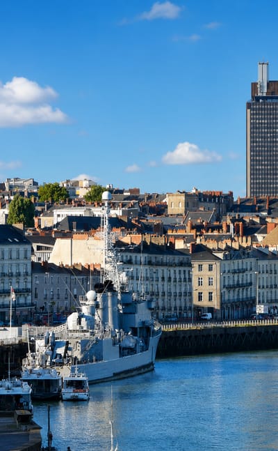 Nantes' Loire waterfront with the Maille-Breze warship, the domed Notre-Dame de Bon-Port basilica and the Tour Bretagne.