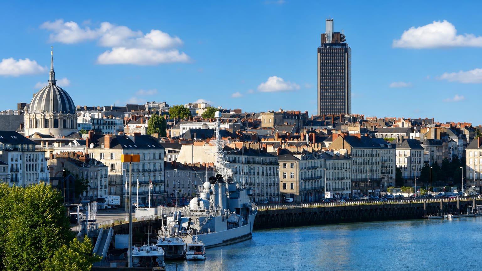 Nantes' Loire waterfront with the Maille-Breze warship, the domed Notre-Dame de Bon-Port basilica and the Tour Bretagne.