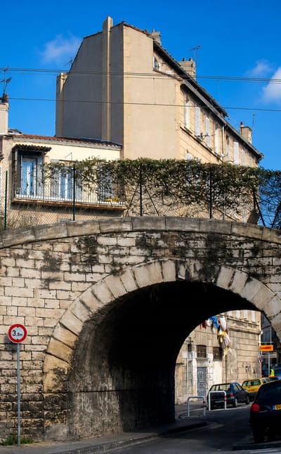 A stone railway arch and old apartment blocks in the working-class Belle de Mai district of Marseille.