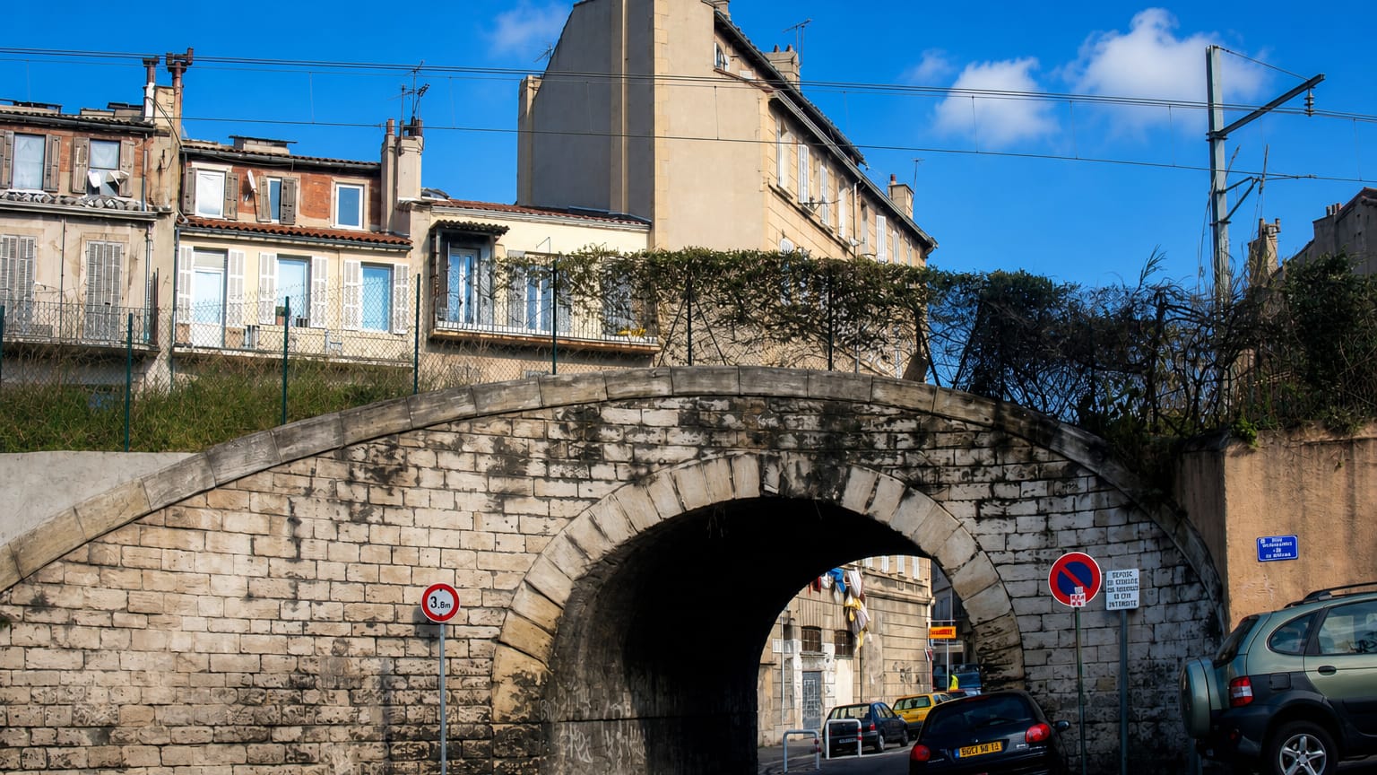 A stone railway arch and old apartment blocks in the working-class Belle de Mai district of Marseille.