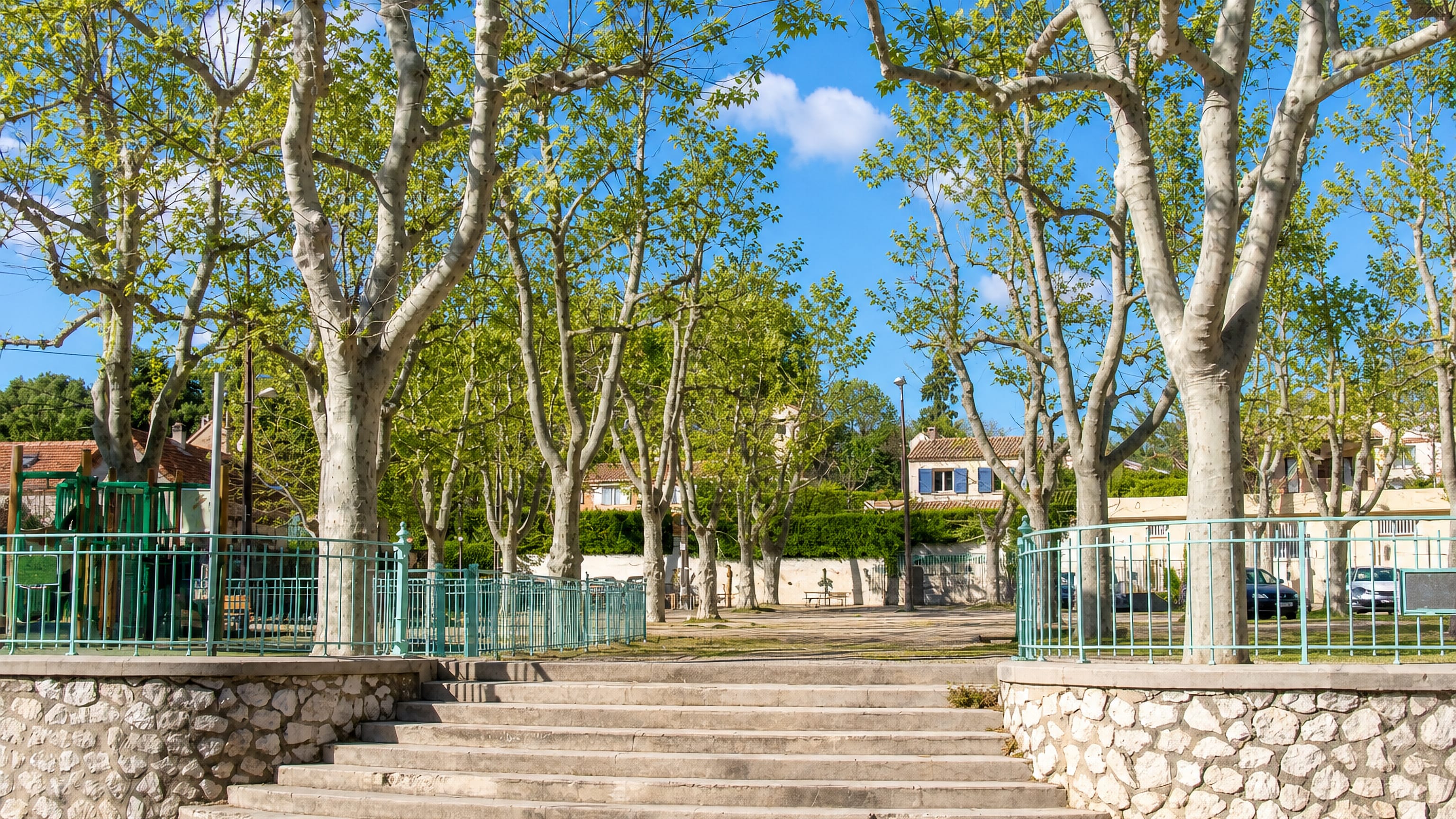 Plane trees shading the village square, steps and stone wall at Eoures in eastern Marseille.
