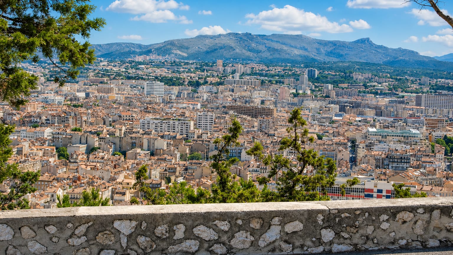 Elevated view over Marseille's terracotta rooftops and dense townscape backed by the surrounding limestone hills.