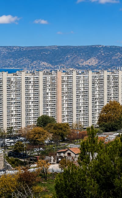 High-rise housing estates in Les Aygalades, northern Marseille, with the sea and coastal hills beyond.