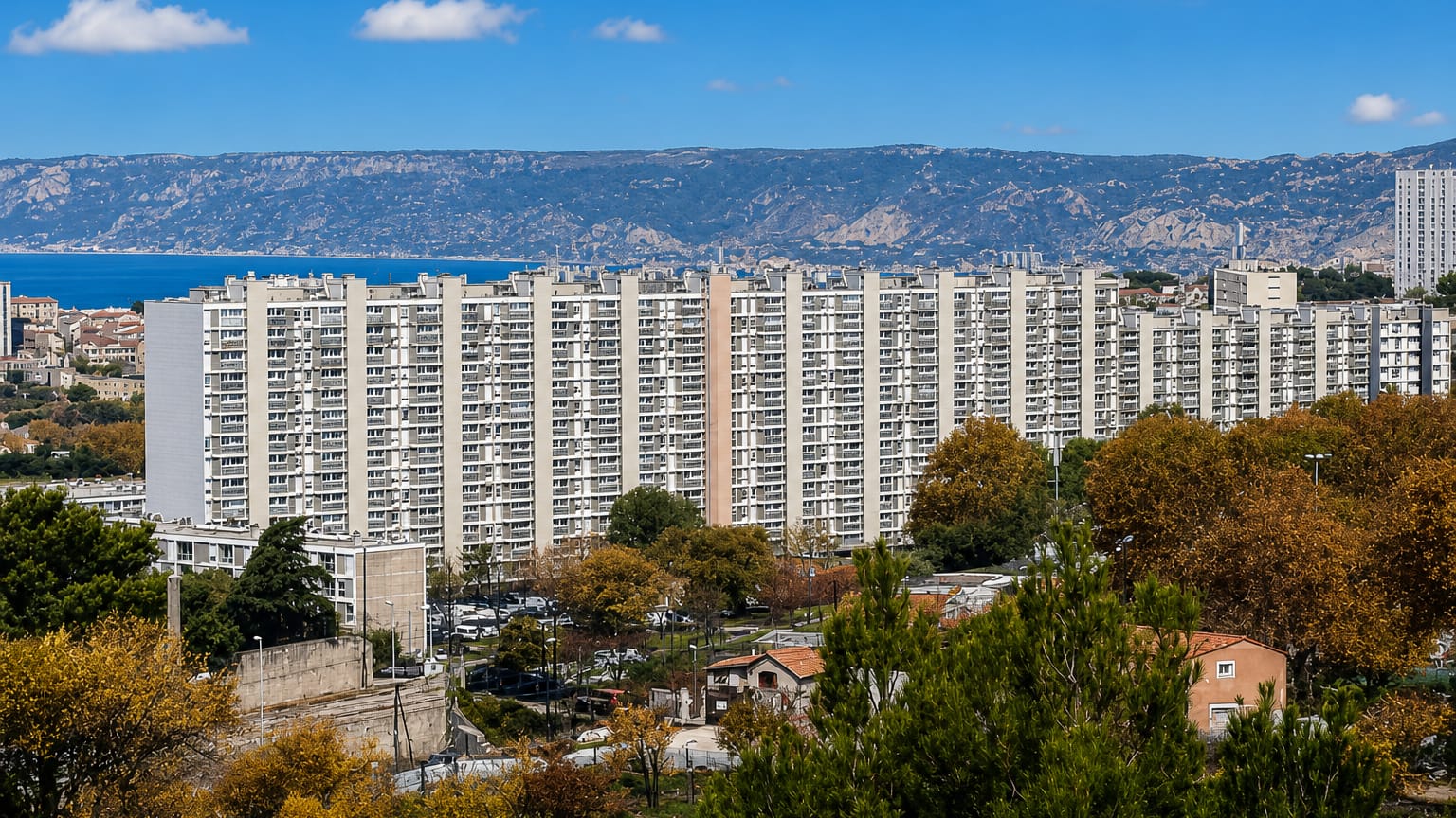 High-rise housing estates in Les Aygalades, northern Marseille, with the sea and coastal hills beyond.