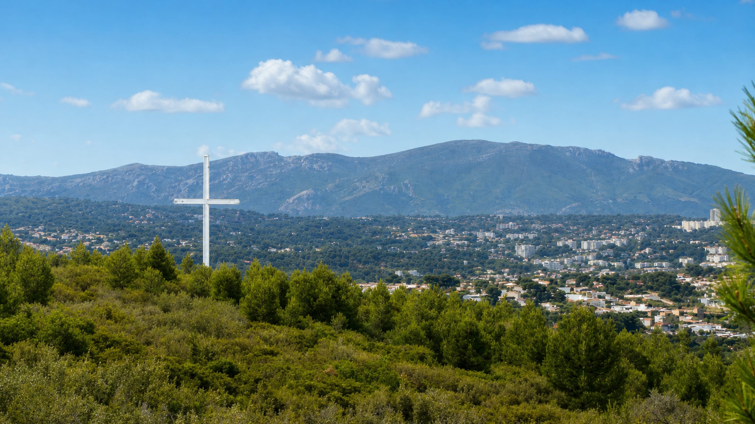 Hilltop cross above pine scrub looking over Les Médecins in Marseille, with the limestone Étoile massif behind.