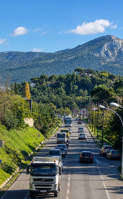 A tree-lined road heading toward limestone hills at Les Trois-Lucs, eastern Marseille.