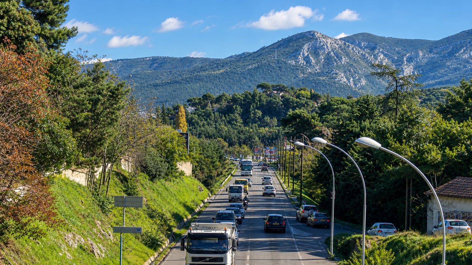 A tree-lined road heading toward limestone hills at Les Trois-Lucs, eastern Marseille.