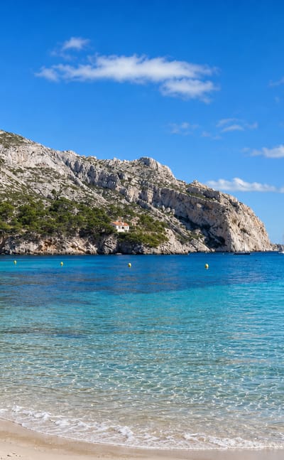 Turquoise water, white limestone cliffs and a sandy beach at the Calanque de Sormiou near Marseille.