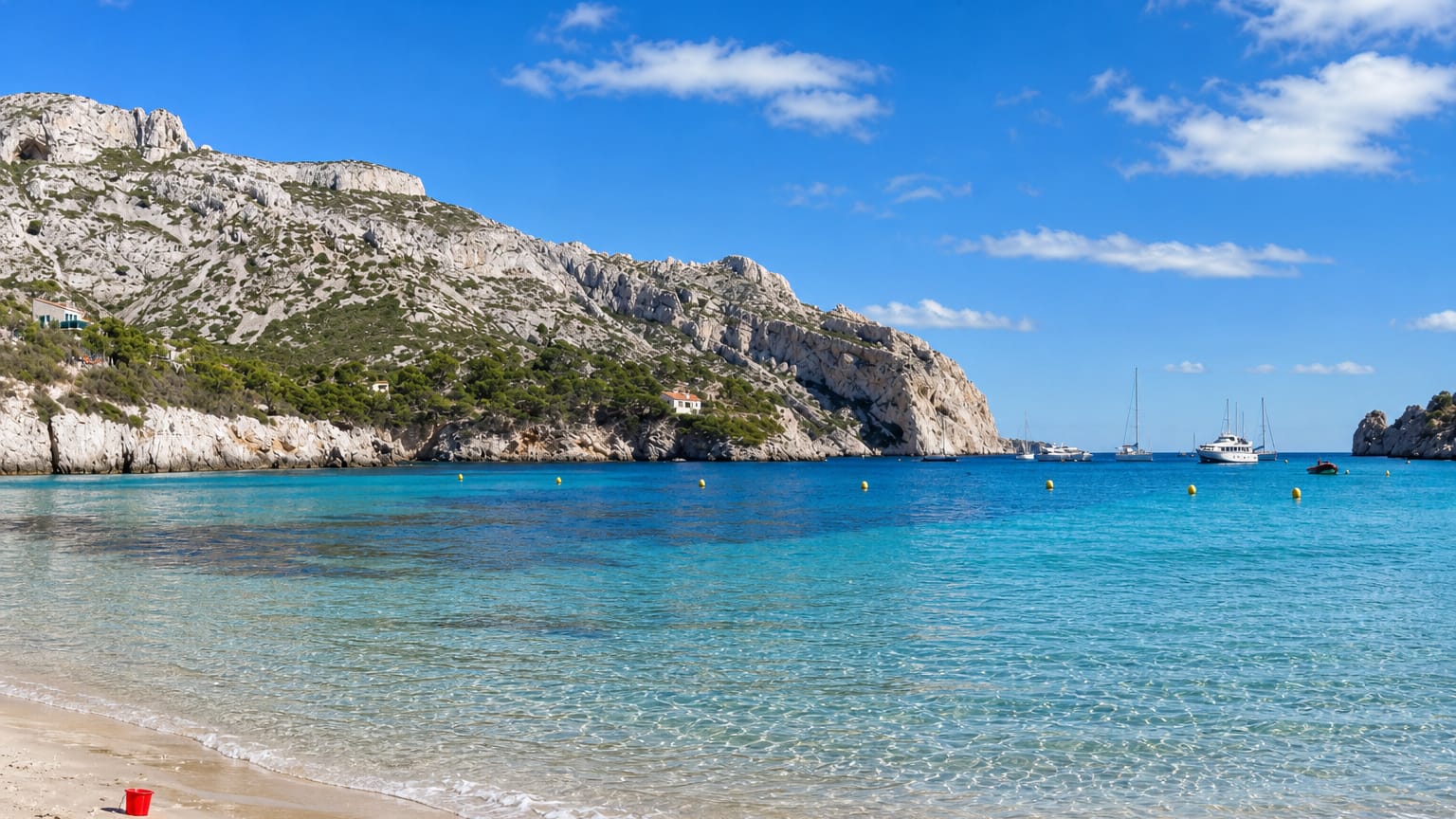 Turquoise water, white limestone cliffs and a sandy beach at the Calanque de Sormiou near Marseille.