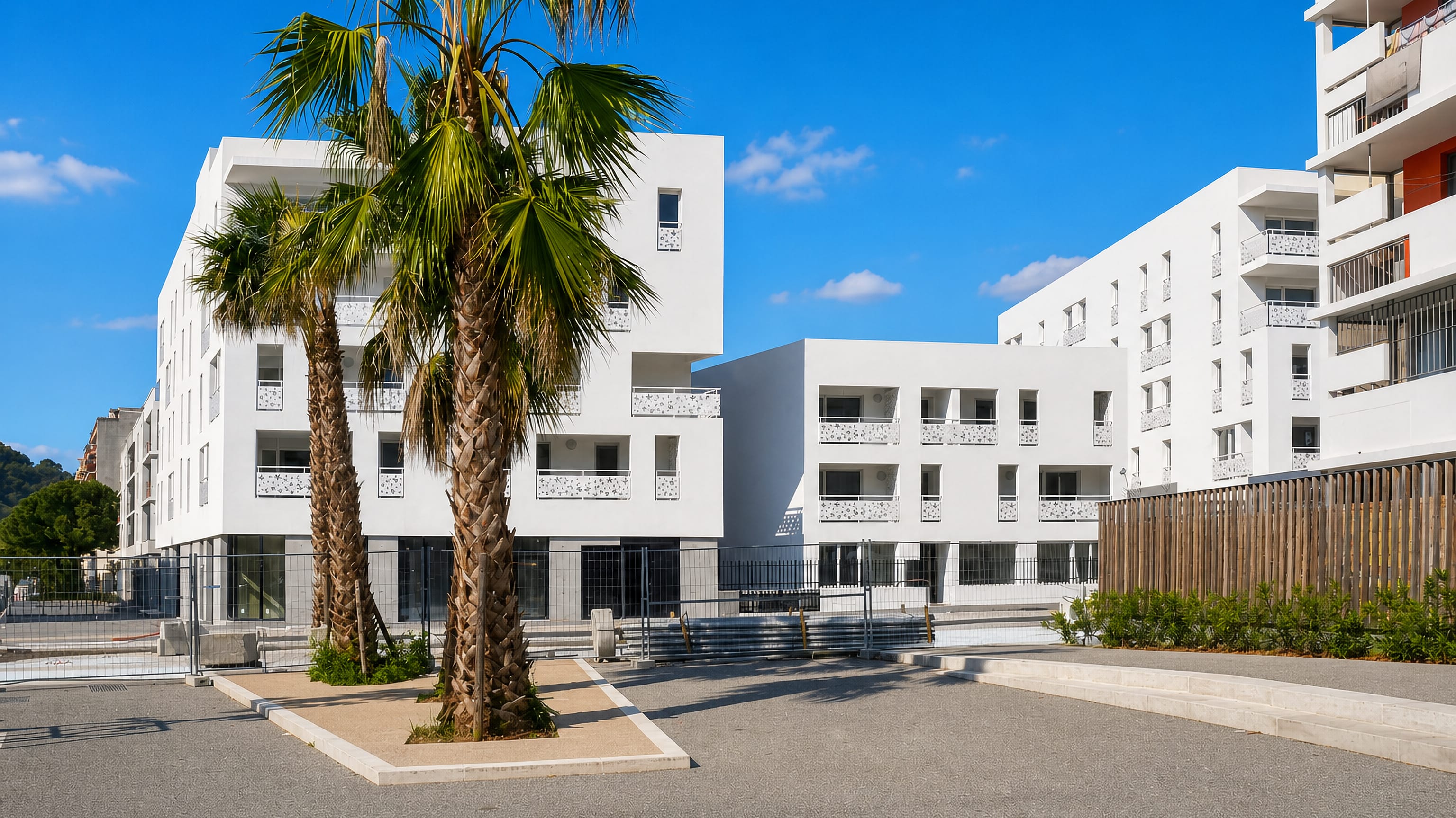 White modern apartment blocks and palm trees on a paved square in L'Ariane, eastern Nice.