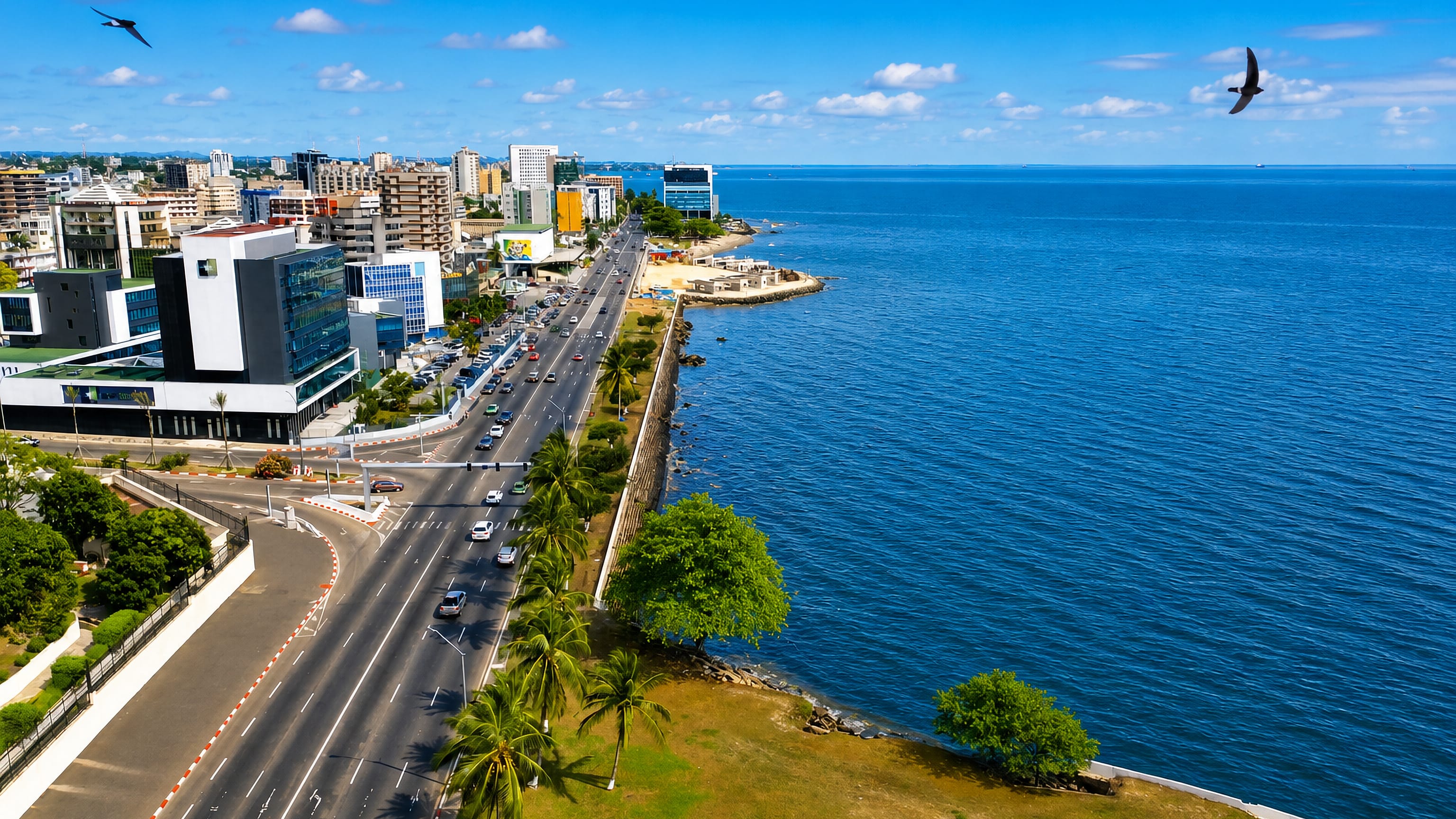 Seafront boulevard curving along the Atlantic past Libreville's mid-rise skyline and palm trees, Gabon.