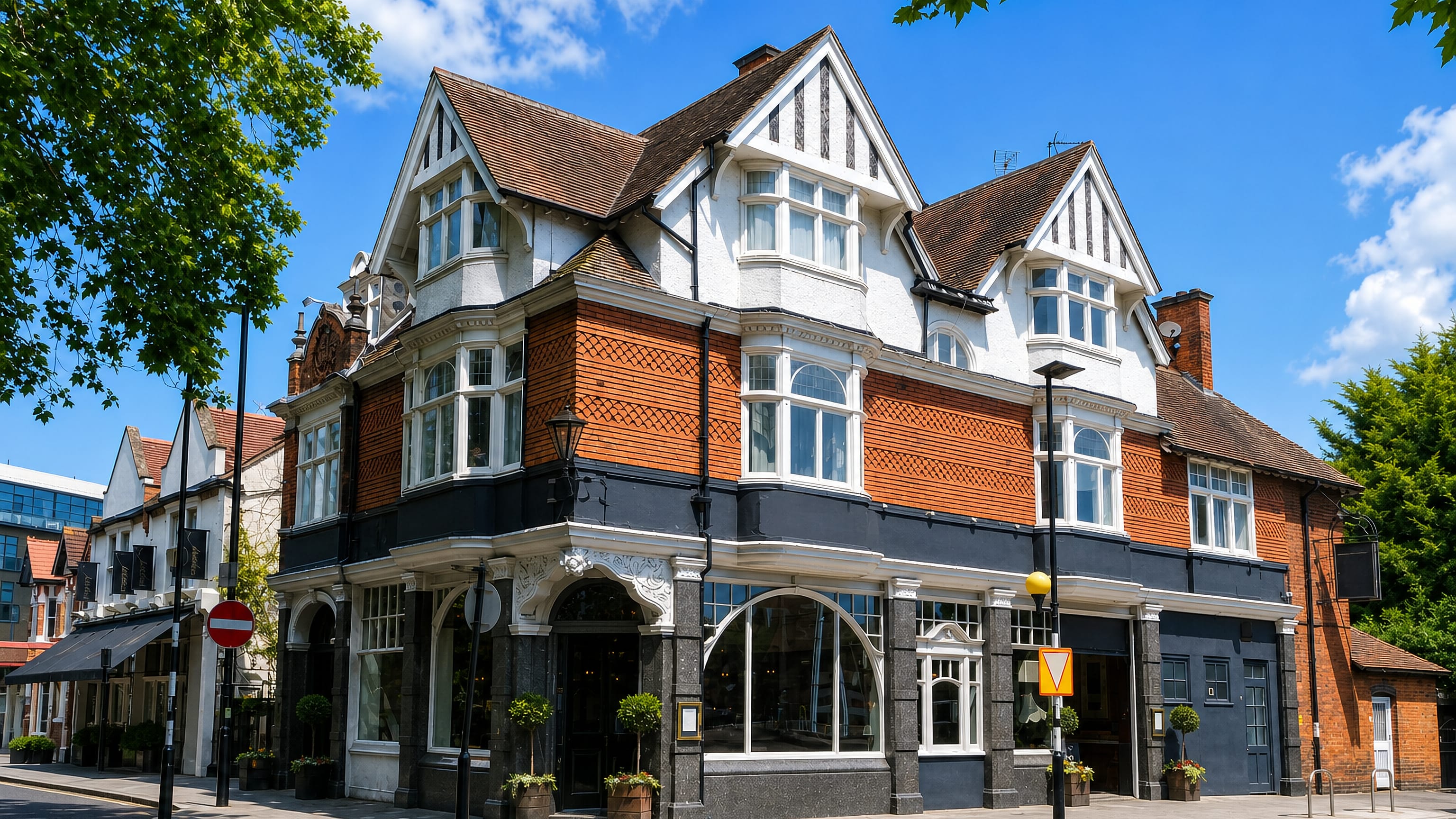 Victorian corner pub in red brick with mock-Tudor gables on a sunny street in Acton Green, London.