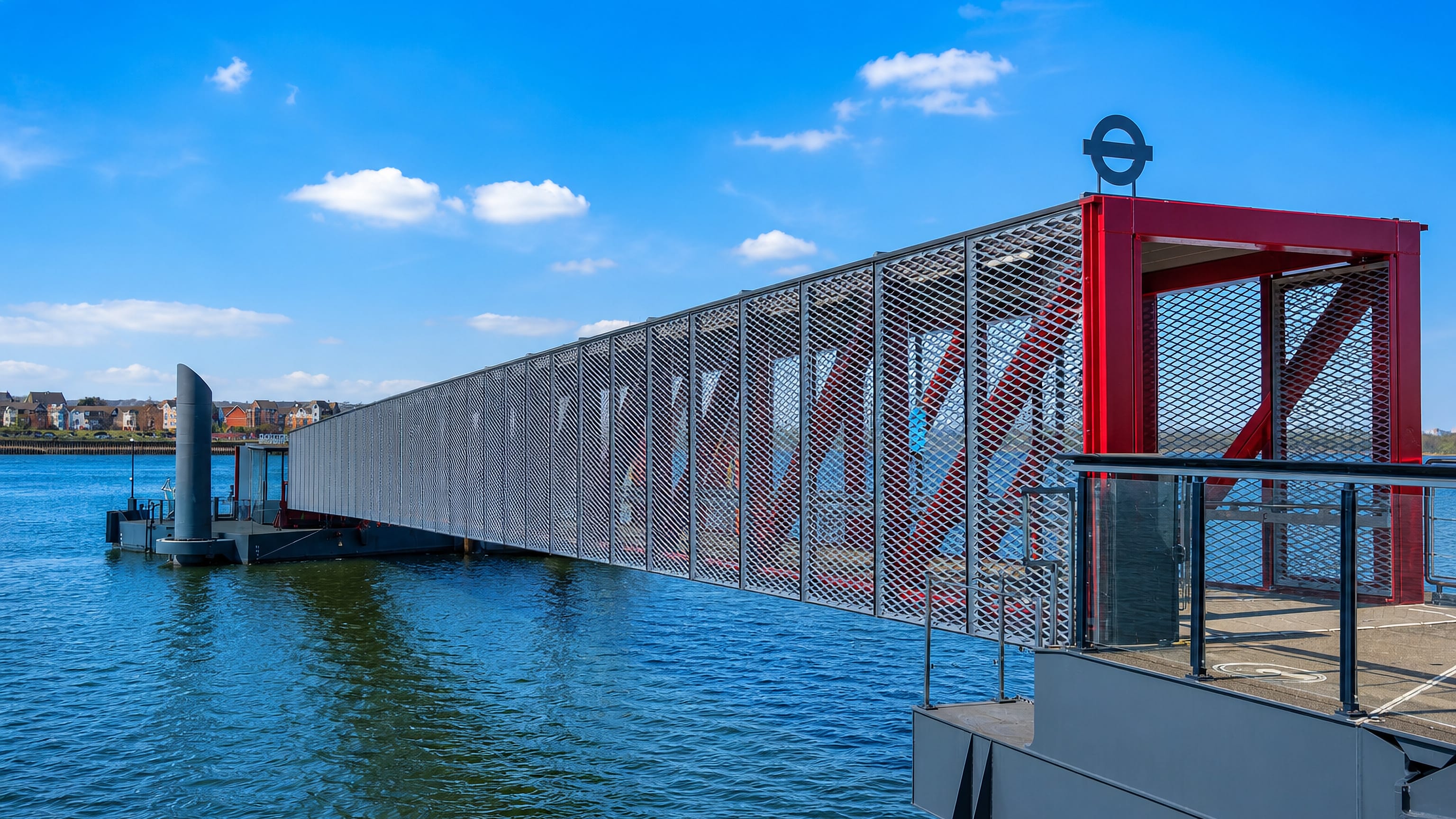 Riverside pier walkway with a red entrance gate on the Thames at Barking Riverside, east London.