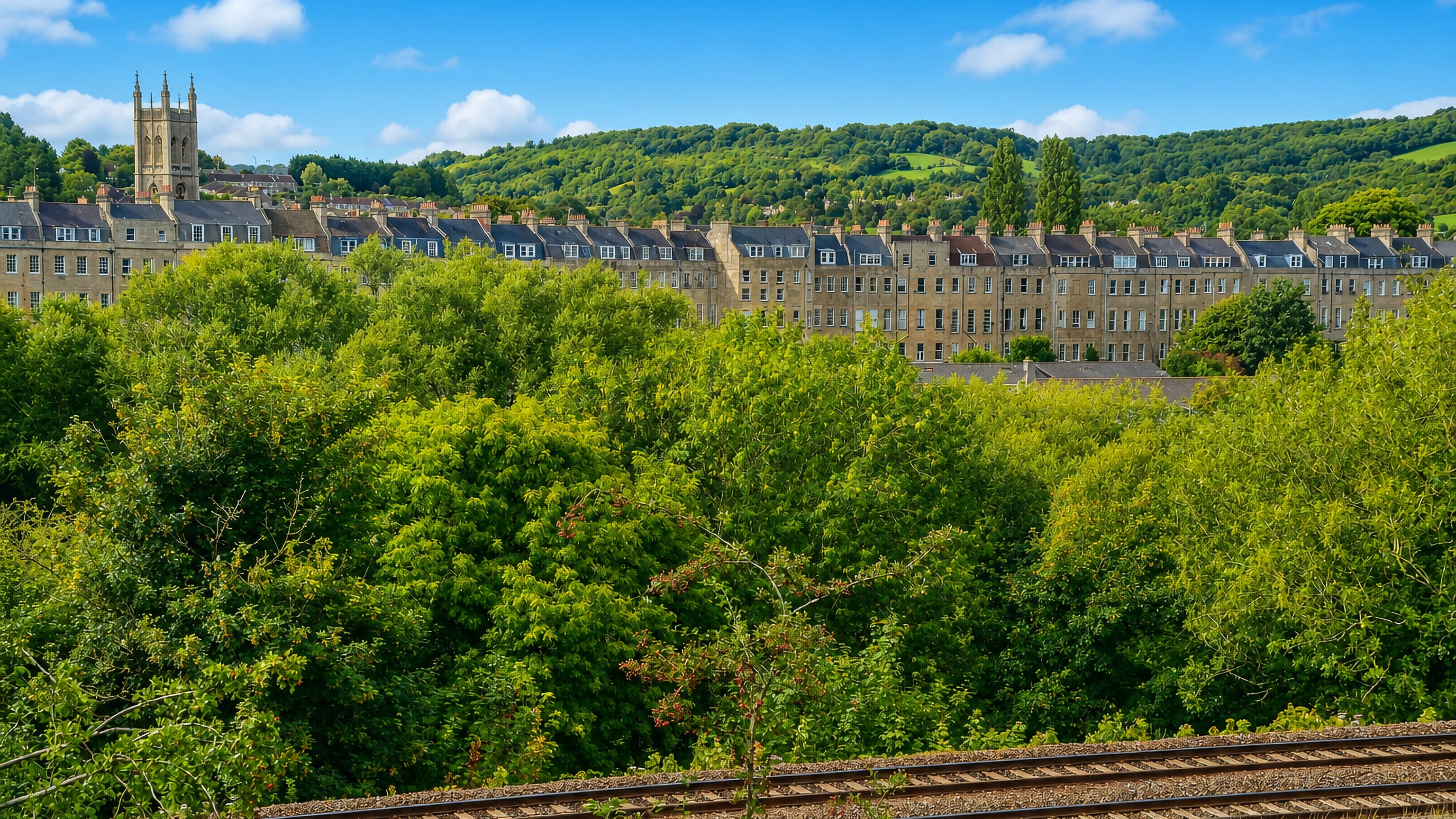 Bath stone terraces and St Saviour's church tower on the hillside at Larkhall, Bath, above the railway.