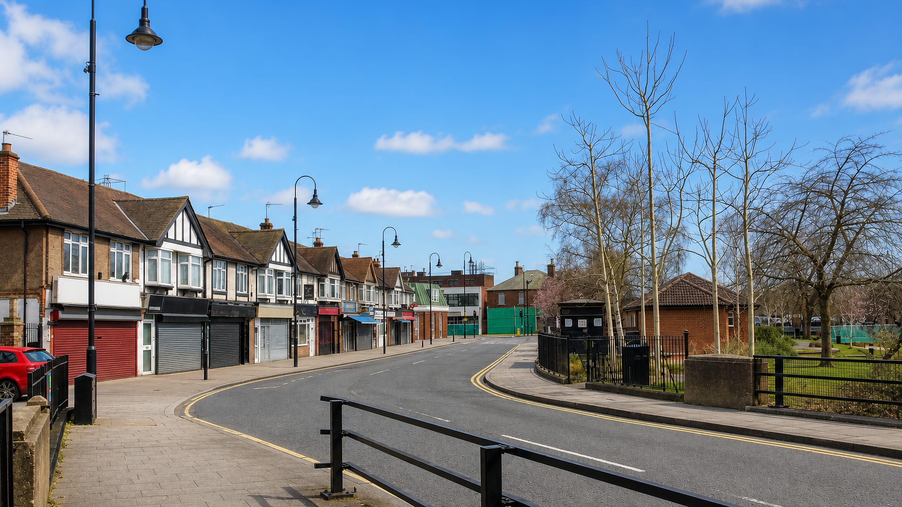 Parade of mock-Tudor shops beside a curving road and iron railings in Crayford, southeast London.