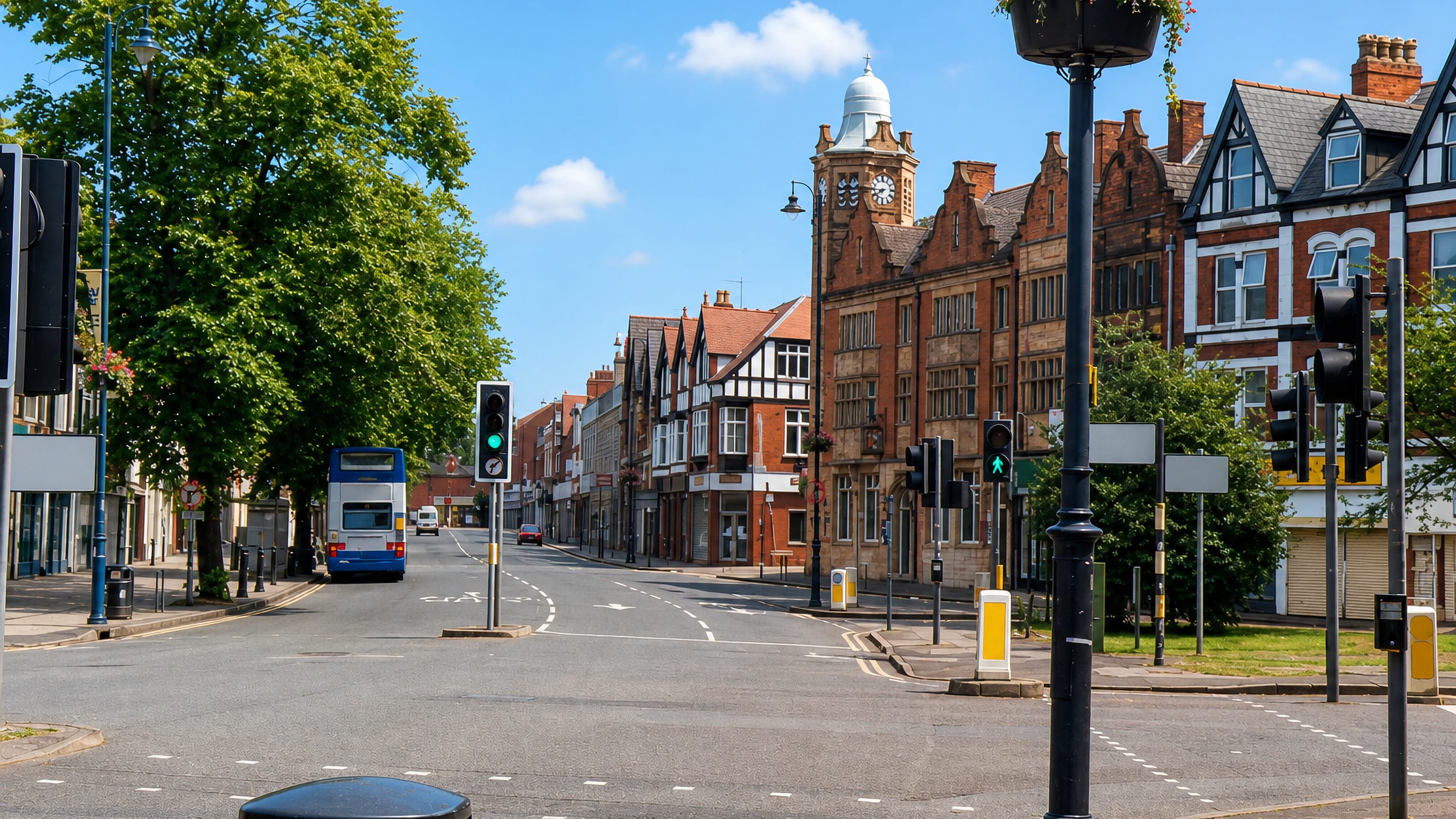 Victorian red-brick shopfronts and a clock tower on the high street in Moseley, Birmingham, with a bus passing