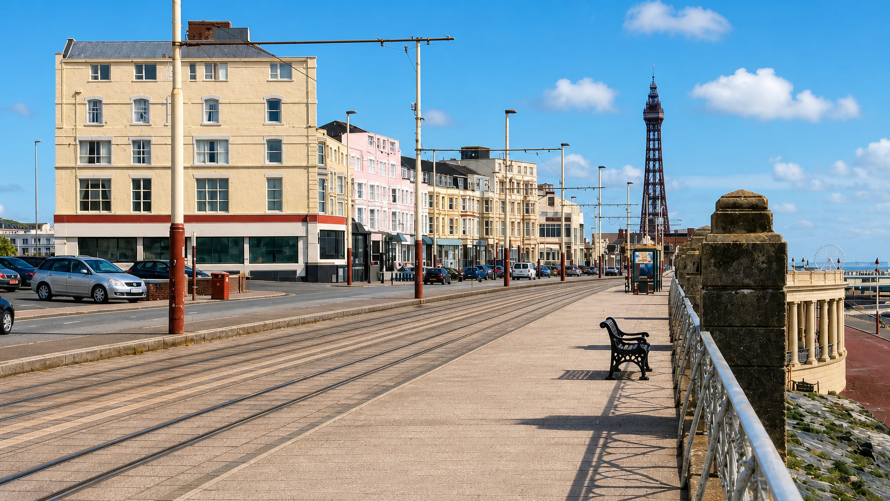 Blackpool Tower and the seafront tramway seen along the North Shore promenade past Victorian hotels.
