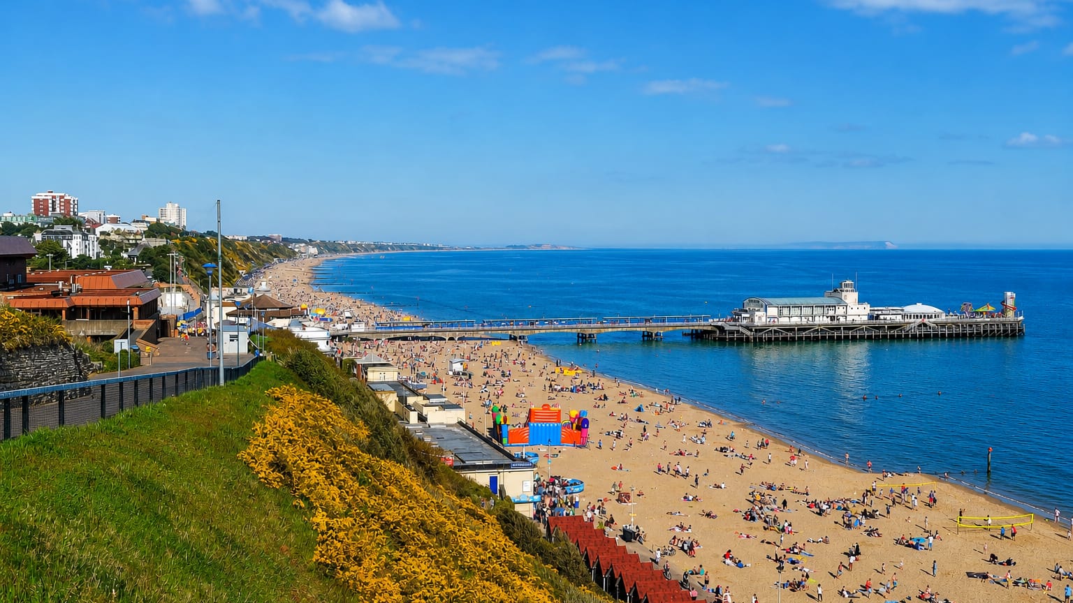Bournemouth beach and pier stretching along the coast below the clifftop gardens on a sunny day.