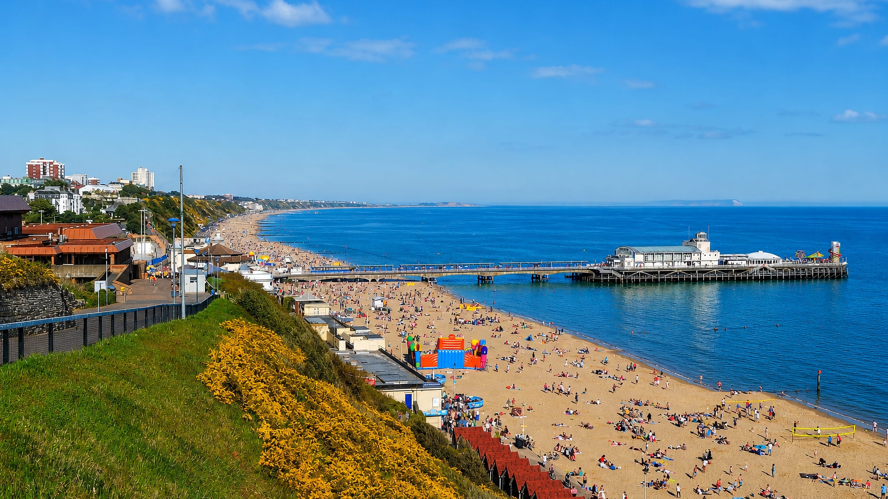 Bournemouth beach and pier stretching along the coast below the clifftop gardens on a sunny day.