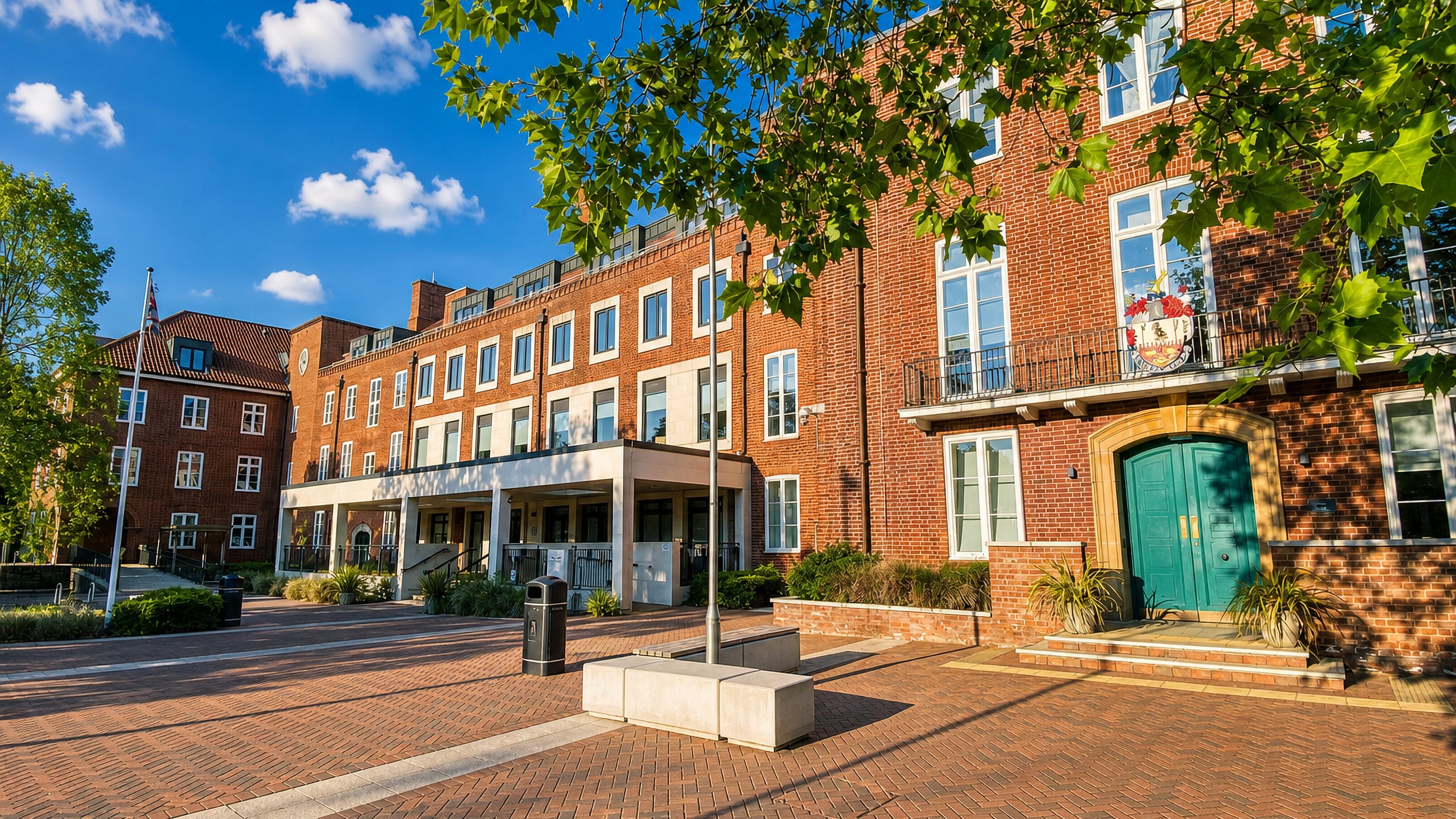 Red-brick civic buildings and a tree-shaded brick-paved plaza in the centre of Brentwood, England.