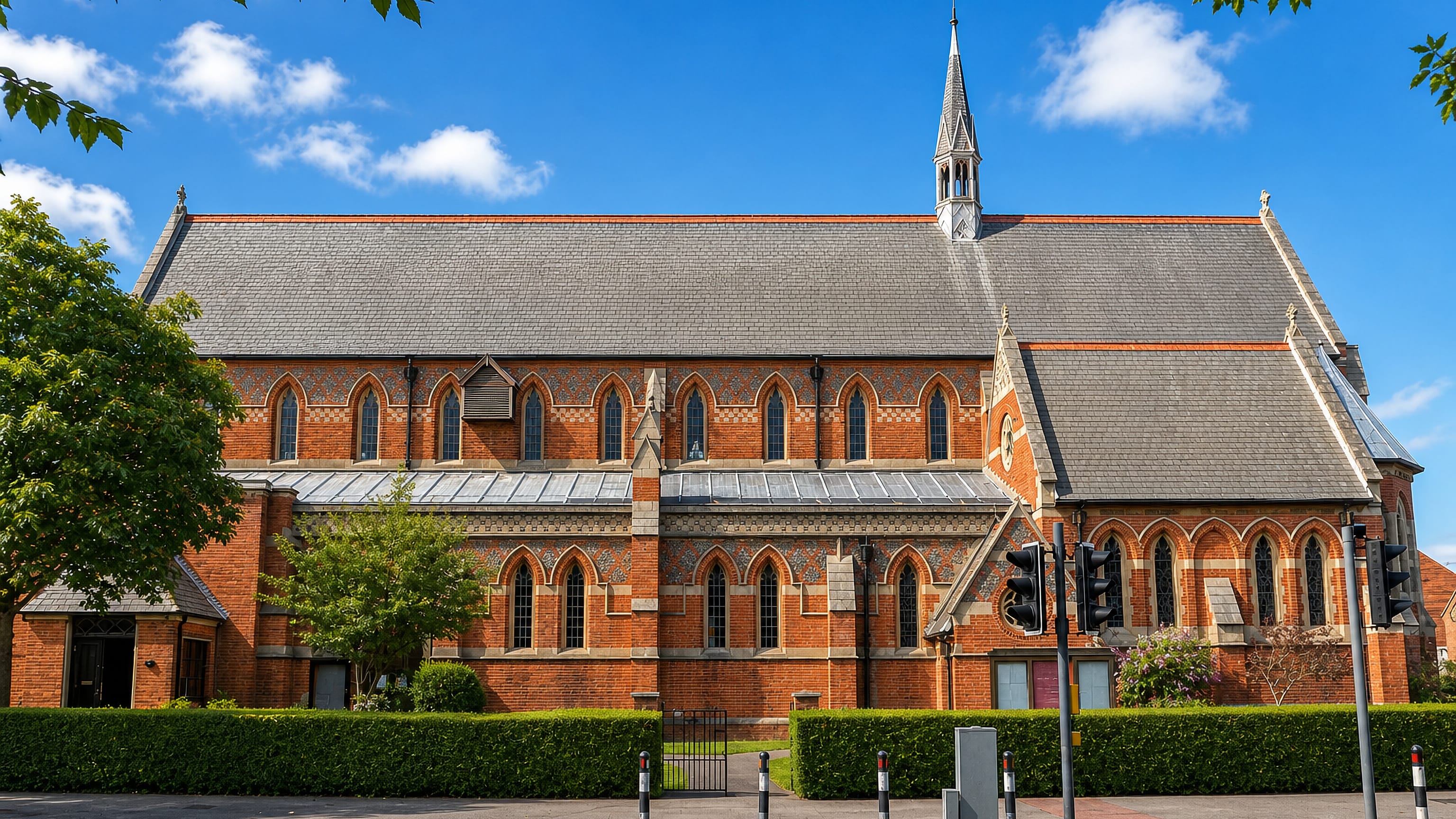Victorian red-brick church with a slender spire beside a main road in Aldrington, Hove.