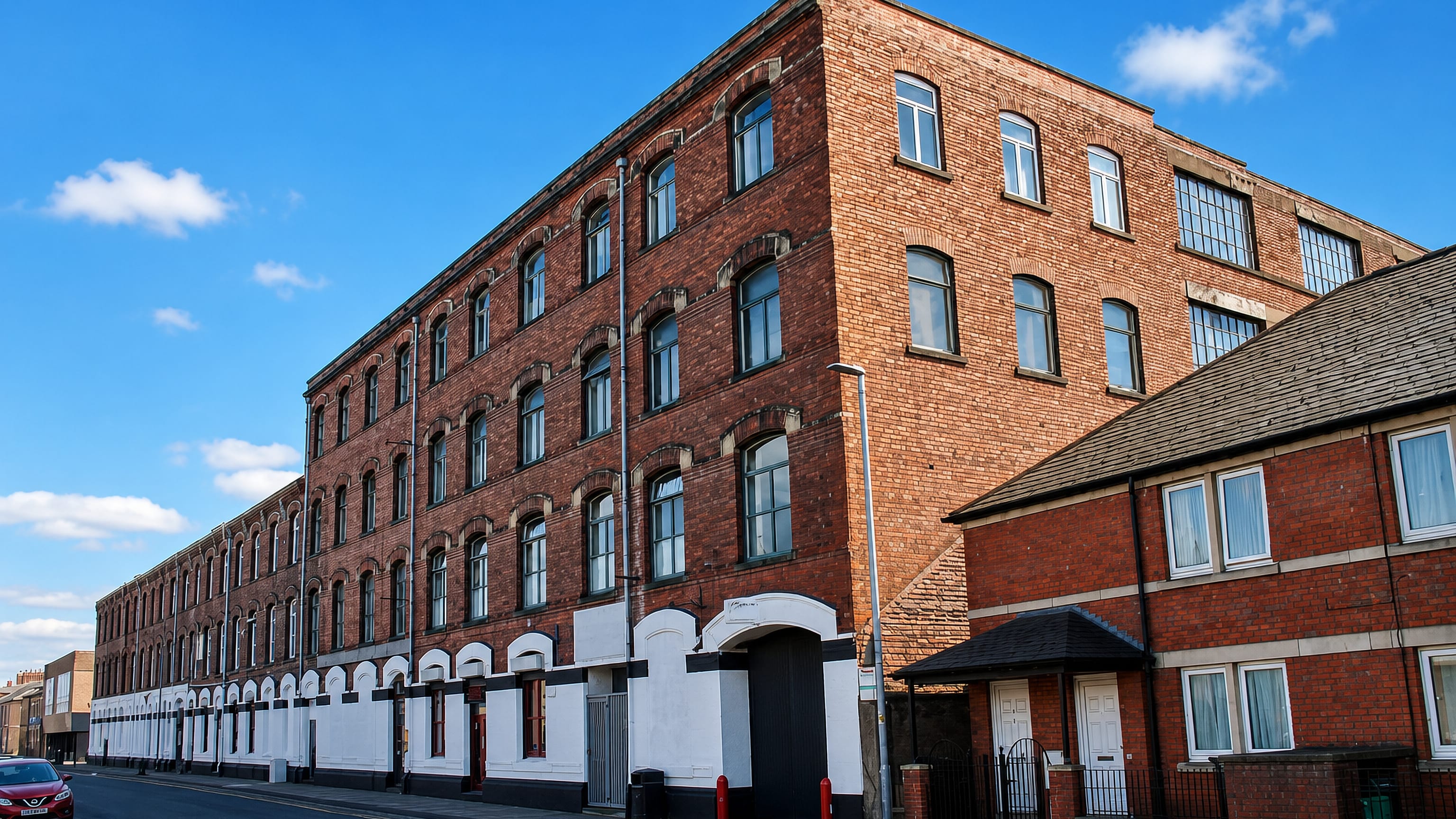 Victorian red-brick mill and terraced houses on a street corner in Denton Holme, Carlisle.