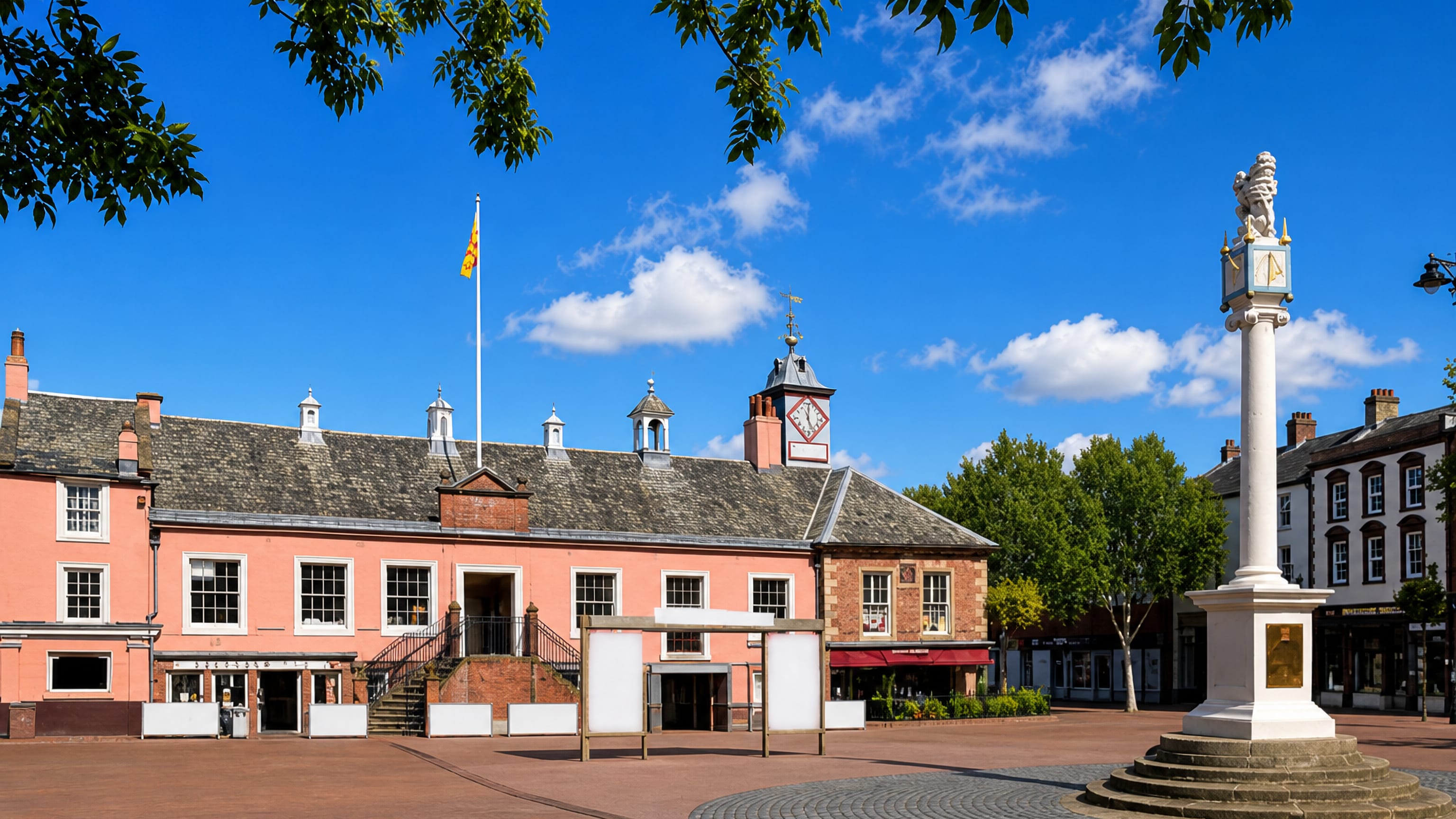 Carlisle's Market Cross and pink-rendered Old Town Hall on the cobbled Greenmarket square in Cumbria, England