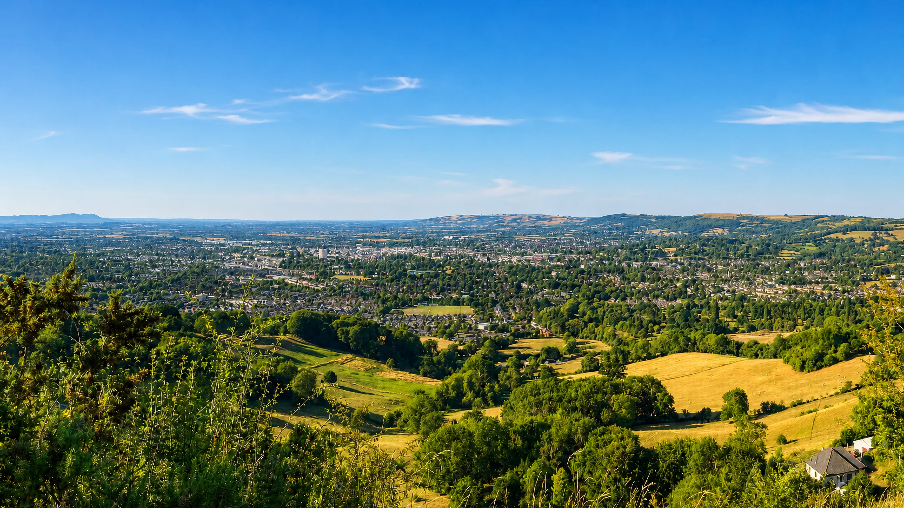 Cheltenham, England, spread across the Severn Vale seen from the Cotswold escarpment on a clear summer day.