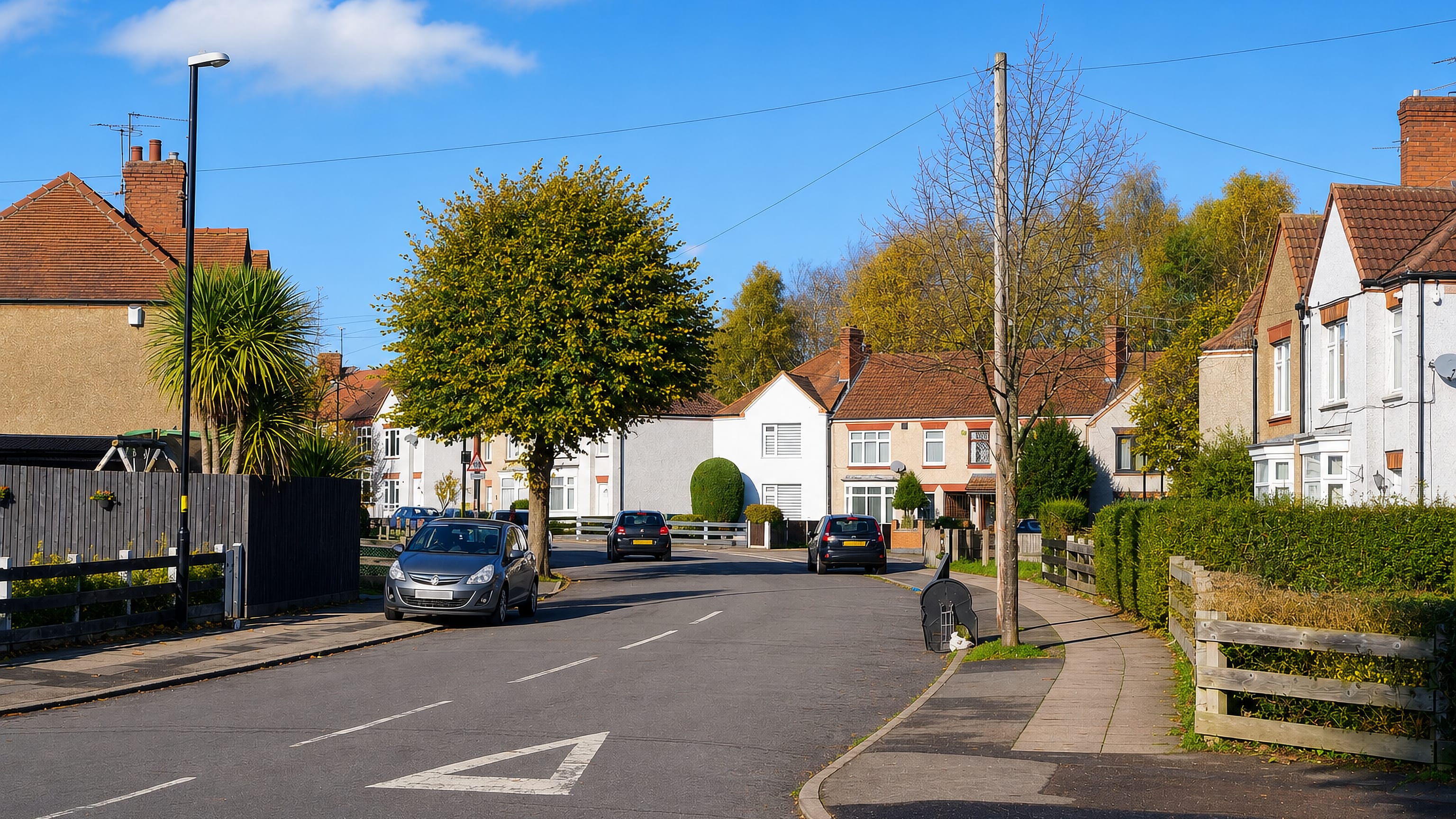 Quiet residential street of interwar semi-detached houses in Holbrooks, Coventry, under a clear autumn sky.