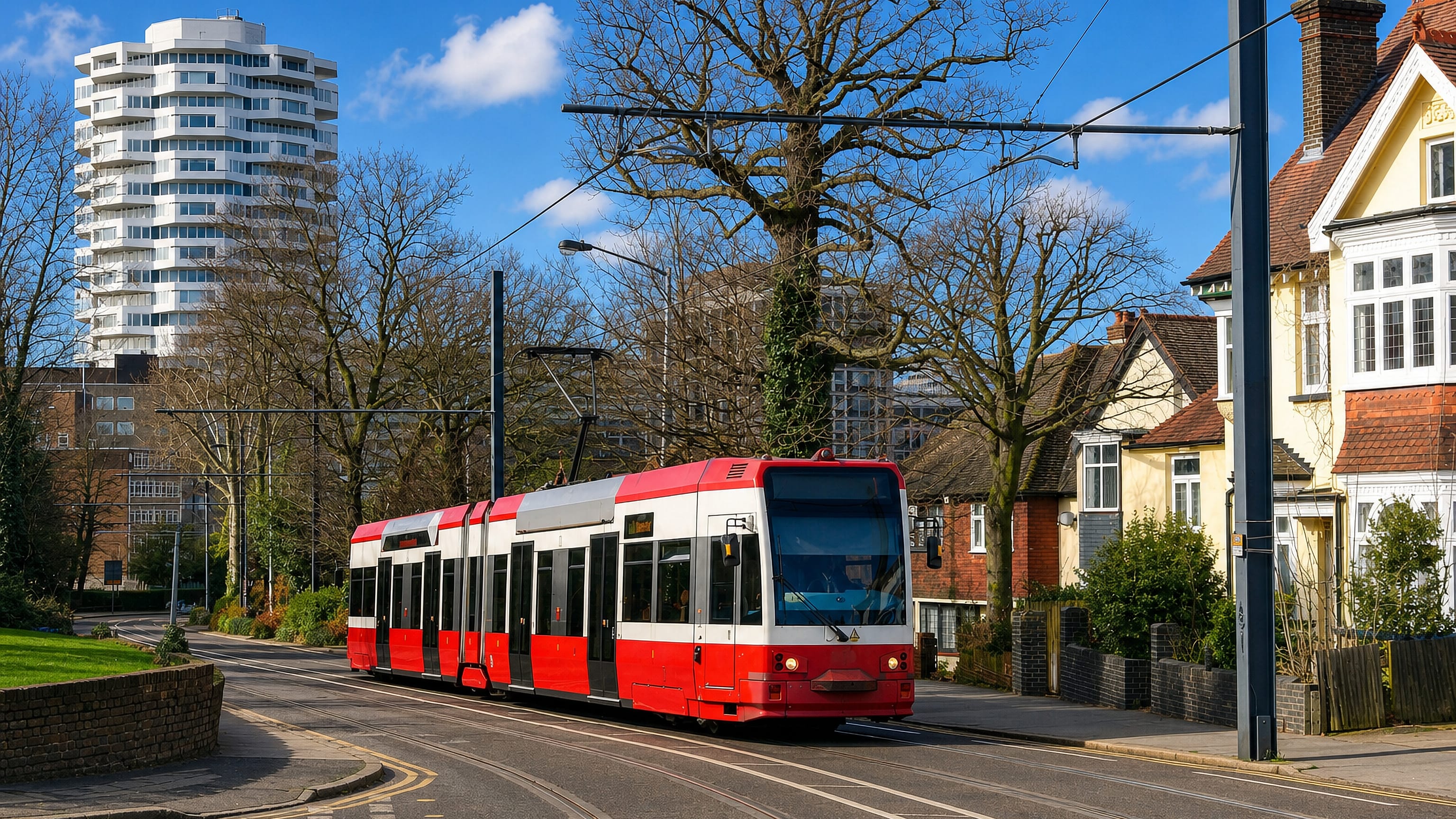 A red-and-white Croydon tram passing suburban houses and a tower block in Addiscombe, south London.