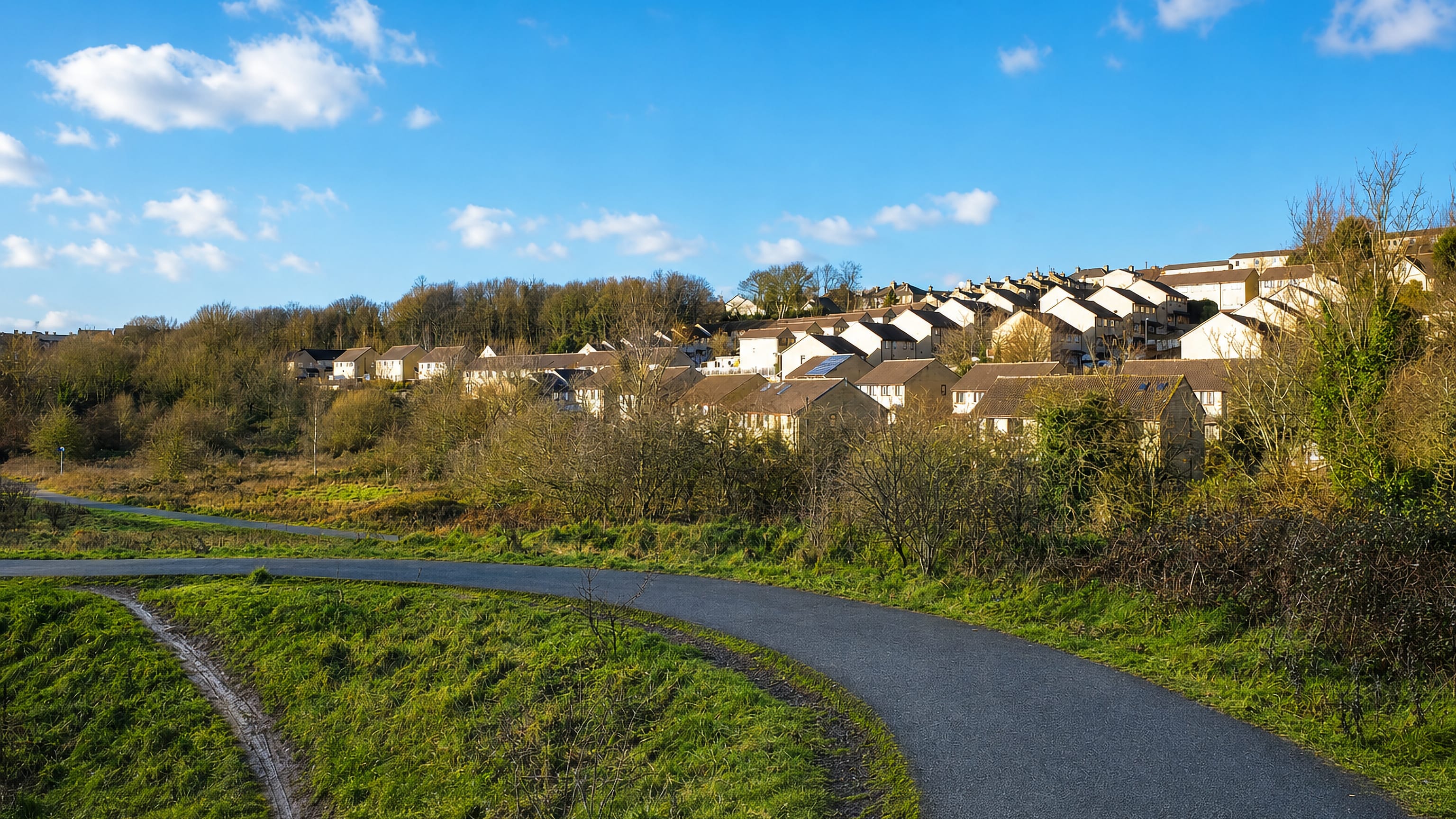 Hillside rows of stone houses above a green valley footpath in Earlsheaton, Dewsbury.