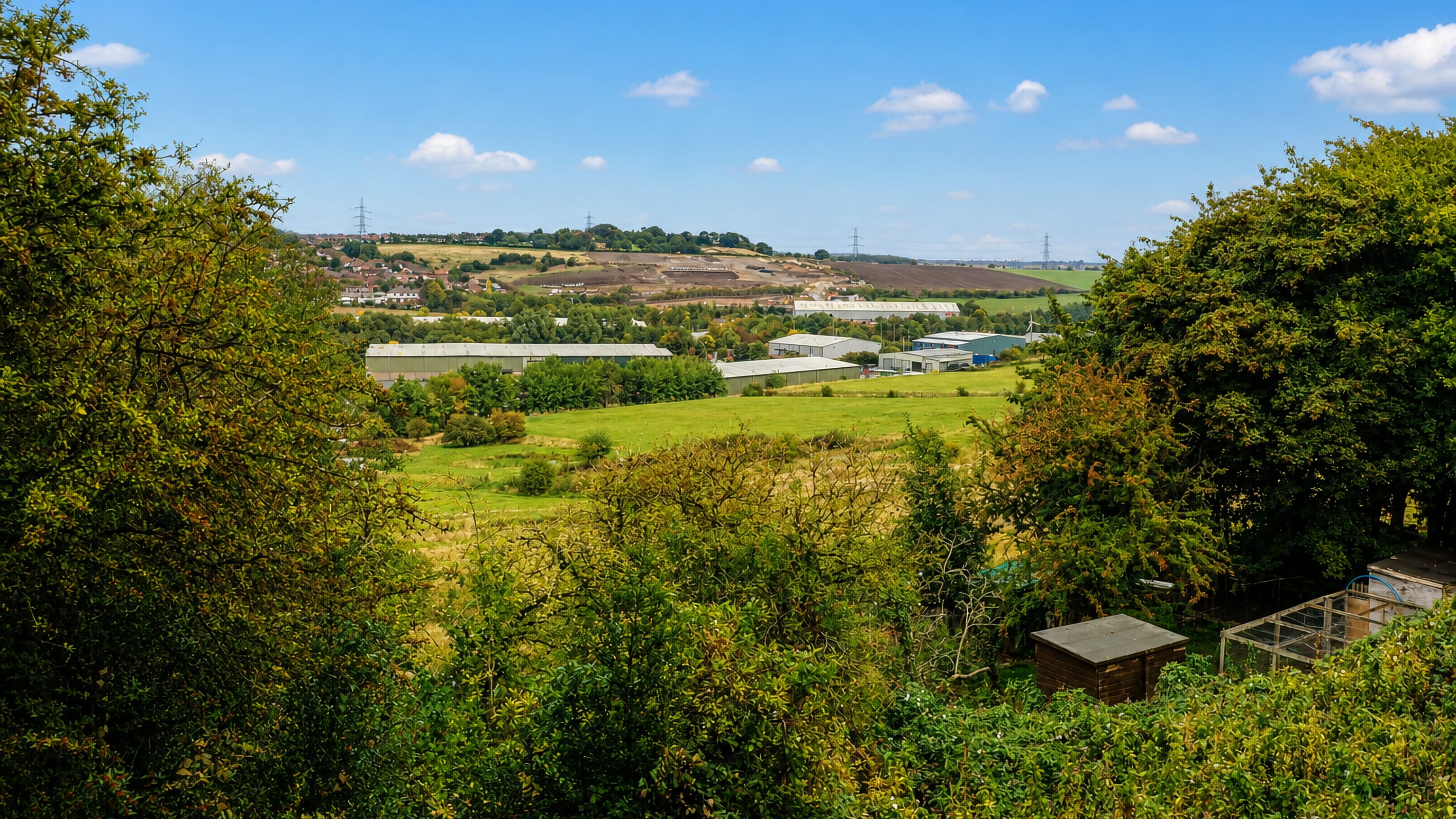 Wooded hillside above industrial units and open fields at Hanging Heaton, Dewsbury