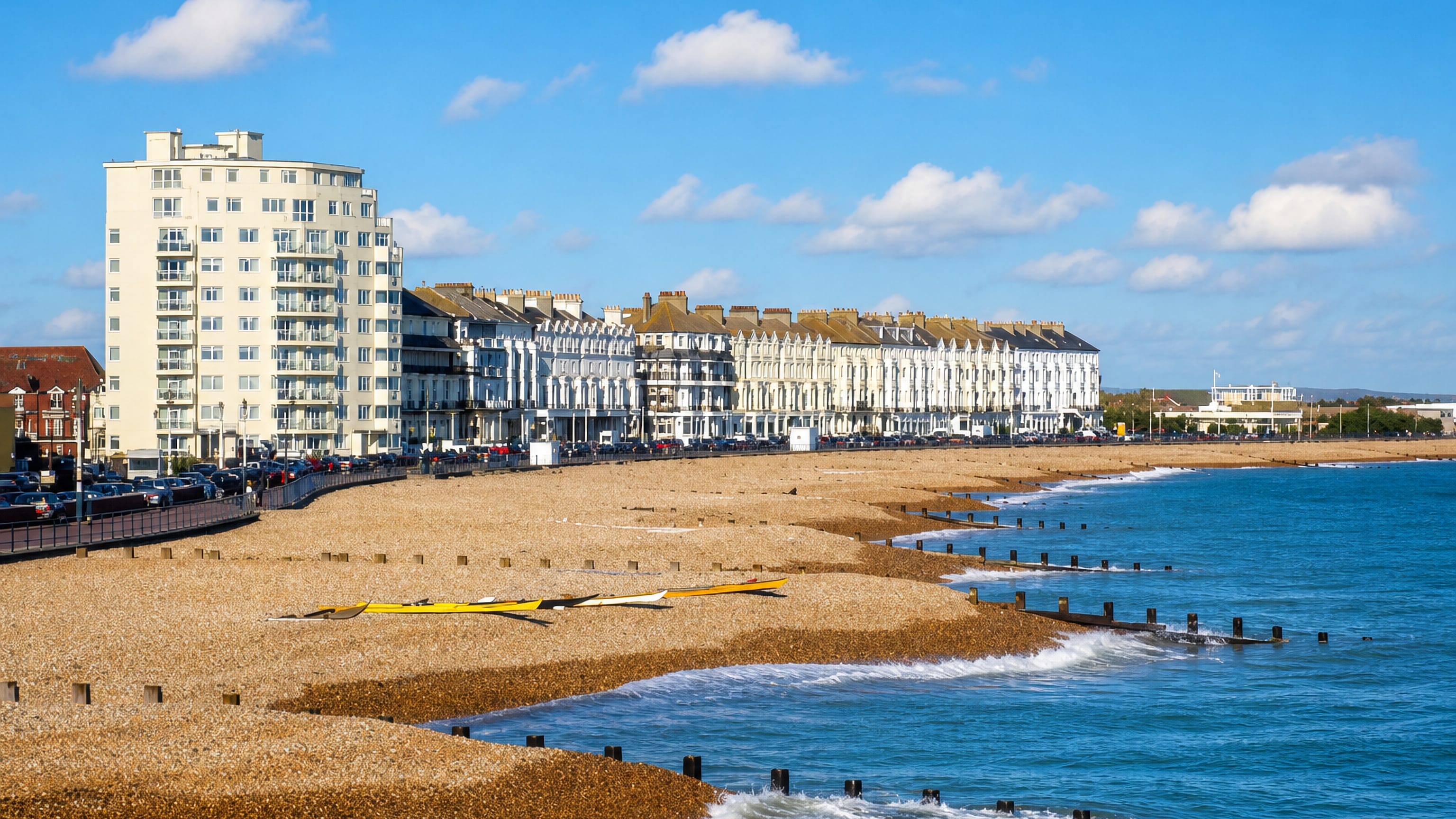 Eastbourne seafront: white Victorian terraces above a shingle beach lined with wooden groynes on the English Channel