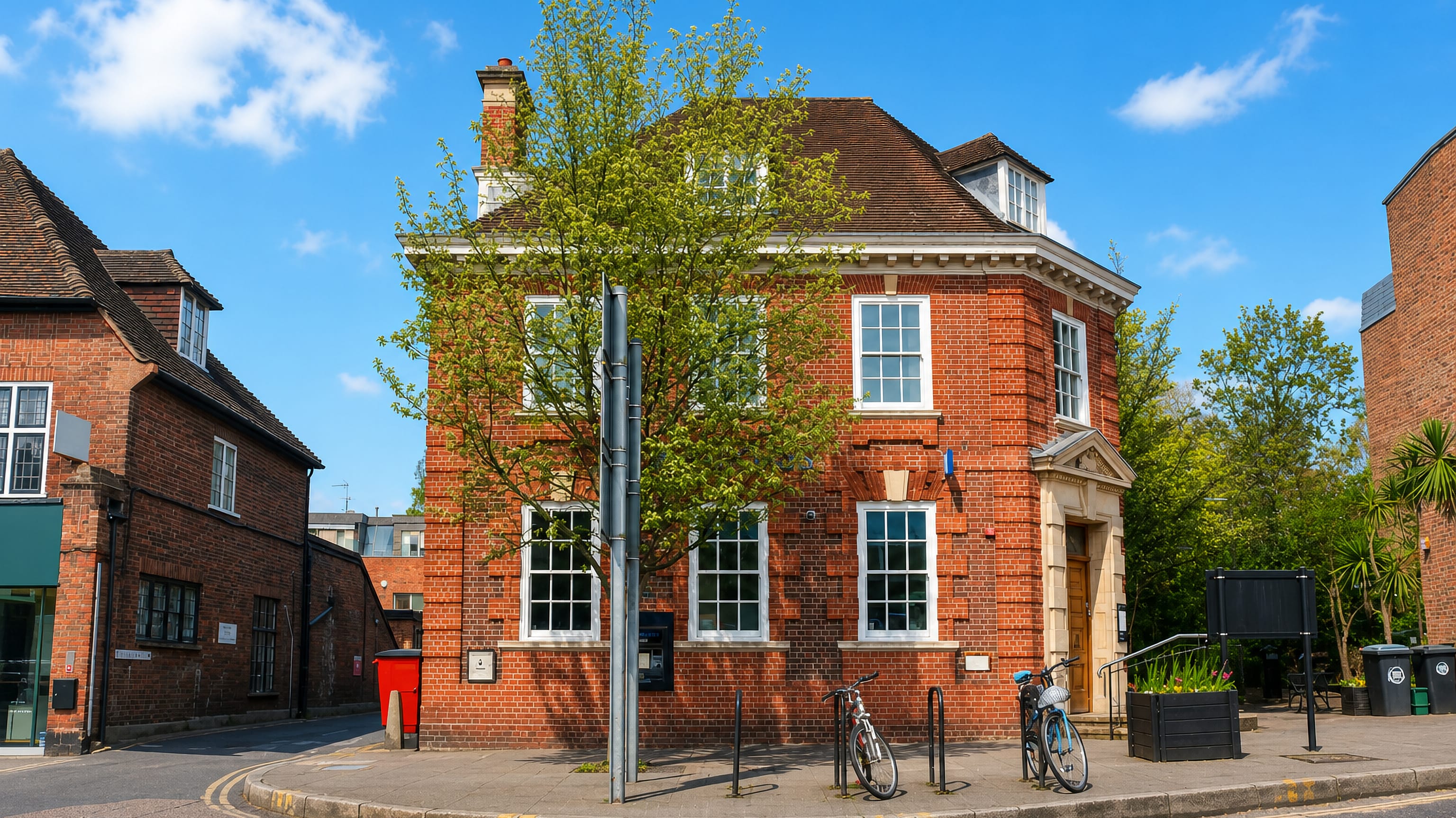 Red-brick Georgian building on a sunlit street corner in Esher, Surrey.